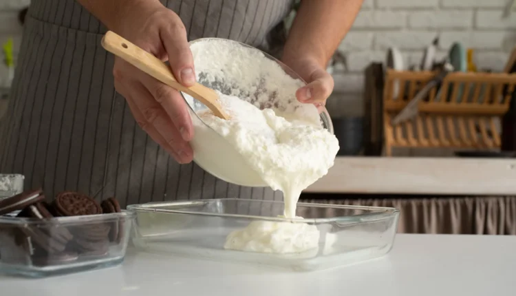 Pessoa despejando creme em uma tigela para preparar uma sobremesa cremosa.