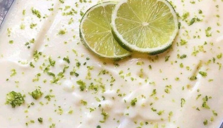 Mousse de limão pronta, decorada com raspas e fatias de limão.