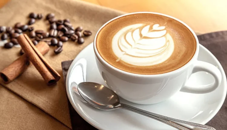 Capuccino caseiro com latte art, servido com grãos de café e canela, ideal para um café da tarde ou noite