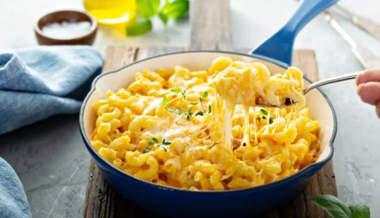 Macarrão com queijo cremoso e delicioso servido em uma panela azul, com queijo derretido esticando