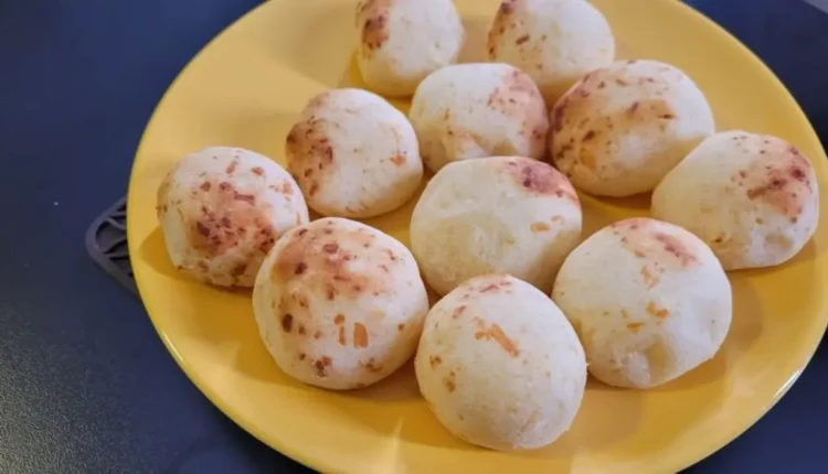 Pães de queijo de batata-doce frescos em um prato amarelo vibrante, apresentando uma textura macia e fofa e leves manchas douradas do cozimento.