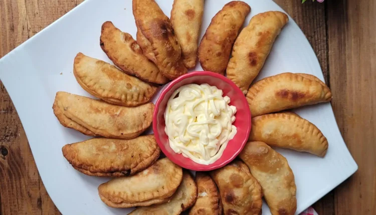 Pastéis fritos com massa sequinha servidos com maionese no centro.