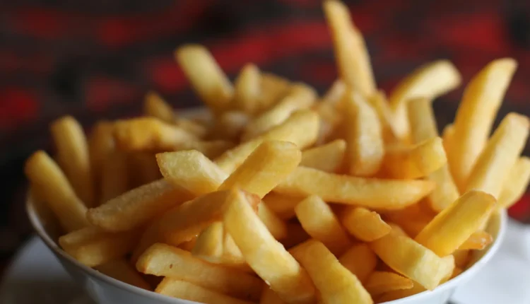 Porção de batatas fritas crocantes em uma tigela branca.