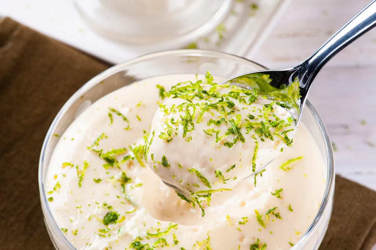Sobremesa cremosa com raspas de limão, servida em copinho, ideal para uma sobremesa refrescante.