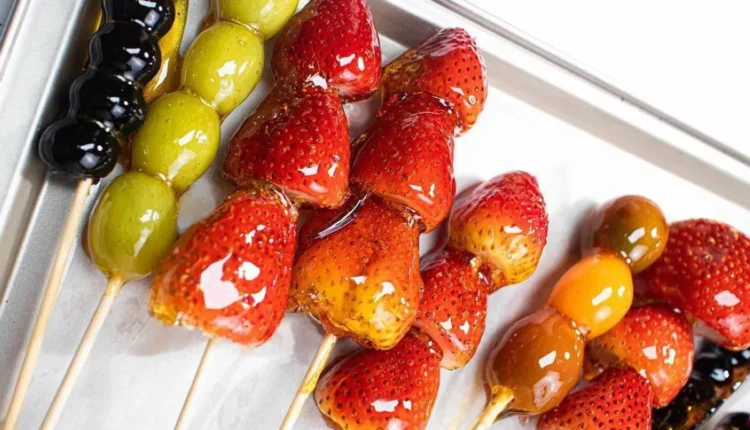 Espetinhos de frutas caramelizadas, incluindo morangos e uvas, representando o Tanghulu chinês.