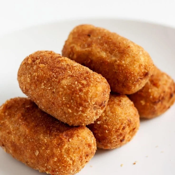 Croquetes de frango crocantes Croquetes de frango dourados e crocantes servidos em prato branco.