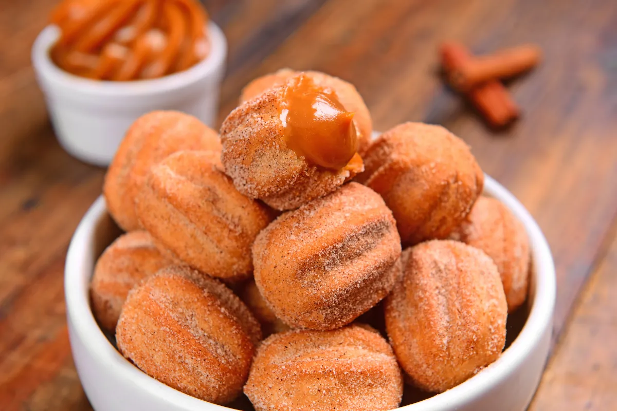 Docinhos de churros com doce de leite prontos para vender Bolinhas de churros com açúcar e canela recheadas com doce de leite.