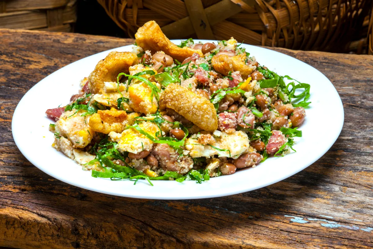 Prato de comida brasileira com feijão, arroz, couve, farofa e torresmo