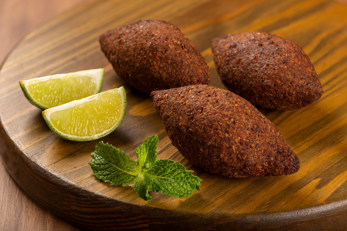 Kibe de carne fritos com limão e hortelã em tábua de madeira Kibe de carne crocantes com fatias de limão e hortelã