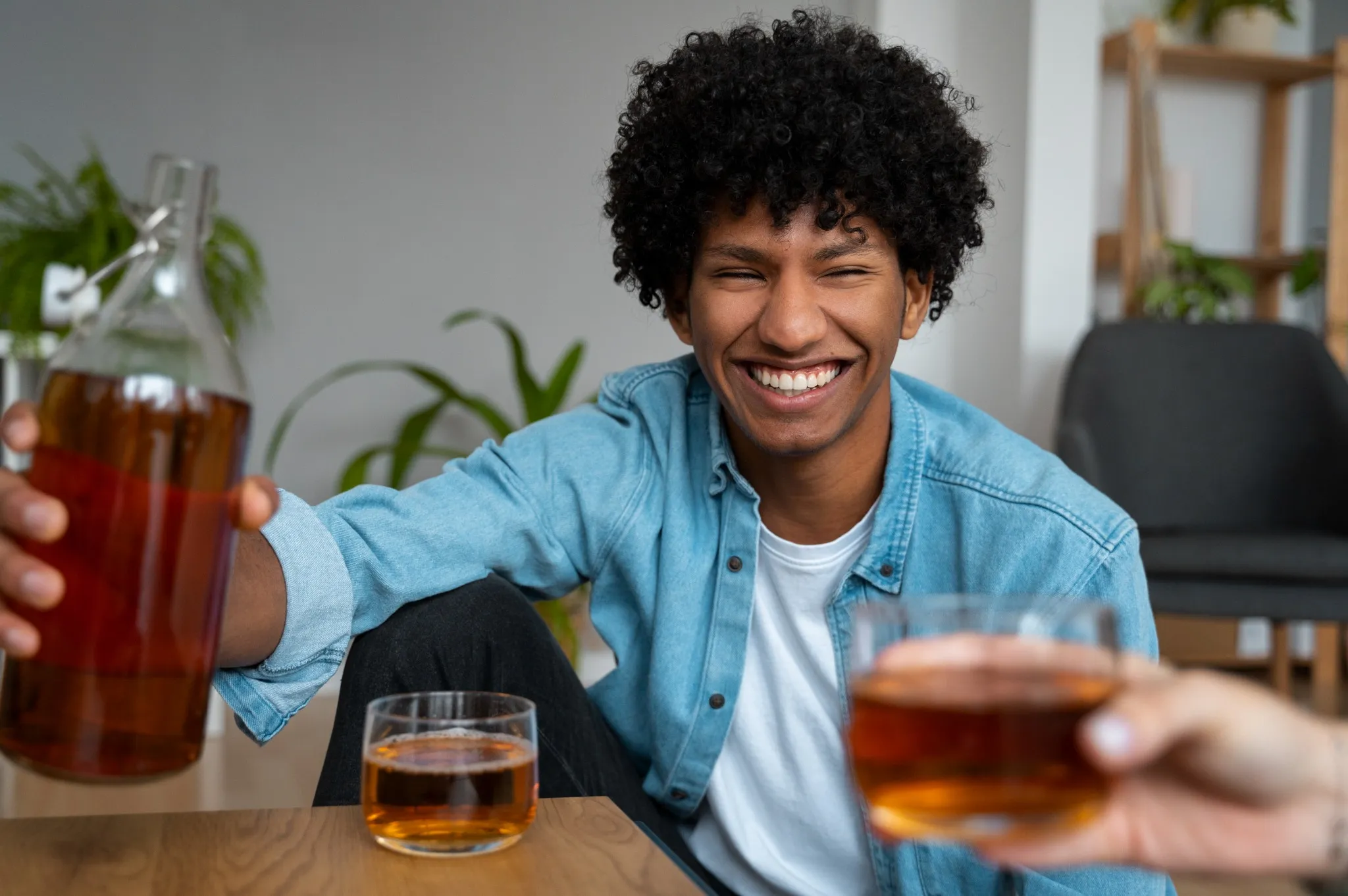 Servindo licor Homem sorridente com camisa jeans servindo bebida em copos baixos.