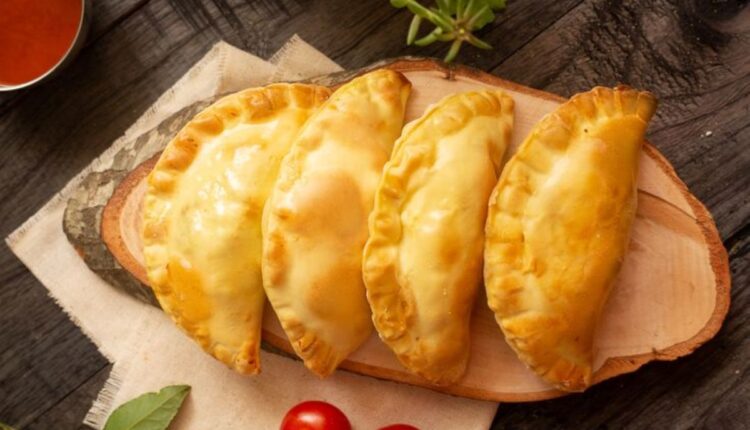 Pastéis dourados recém-assados na air fryer, dispostos sobre uma tábua de madeira rústica.