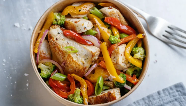 Tigela de frango grelhado com legumes coloridos e frescos, incluindo pimentões, brócolis e cebolas.