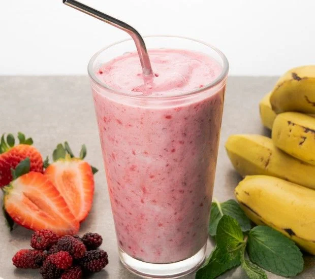 Smoothie de Frutas: Uma opção refrescante e saudável Smoothie de frutas com morangos, framboesas e bananas, servido em um copo alto com canudo