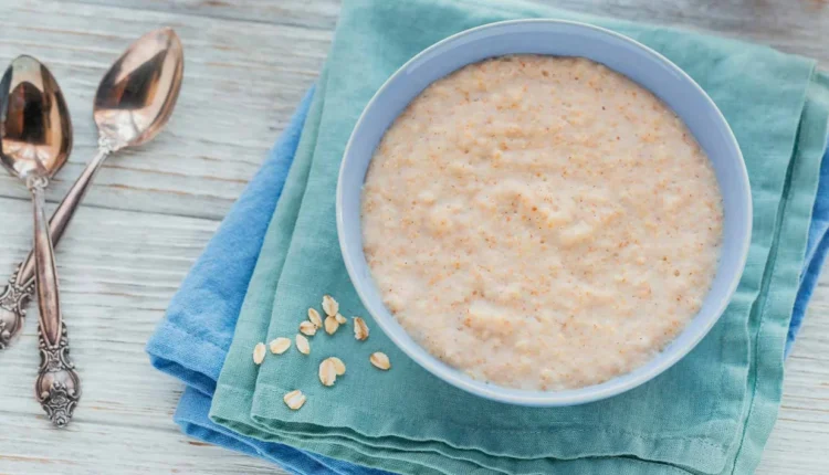 Mingau de aveia sem leite servido em uma tigela azul sobre um pano colorido.