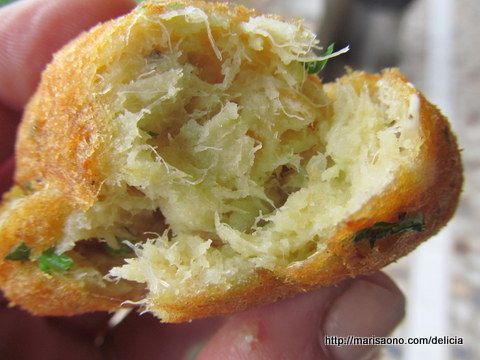 Bolinho de bacalhau partido ao meio, exibindo seu interior macio e cheio de bacalhau desfiado.