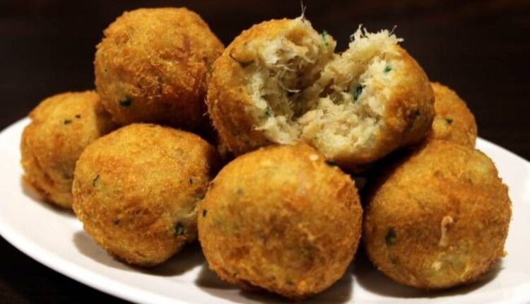 Bolinhos de bacalhau crocantes em um prato branco, mostrando textura interna ao serem partidos.