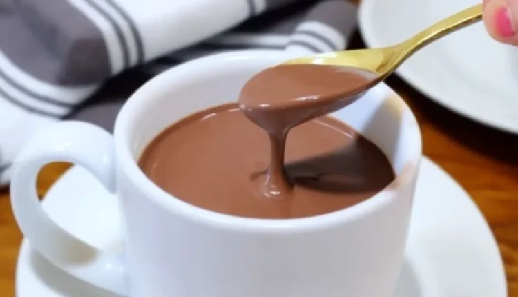 Copo de chocolate quente cremoso com uma colher dourada