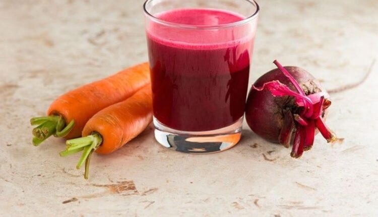 Suco de cenoura com beterraba em copo, acompanhado de cenouras e beterraba fresca